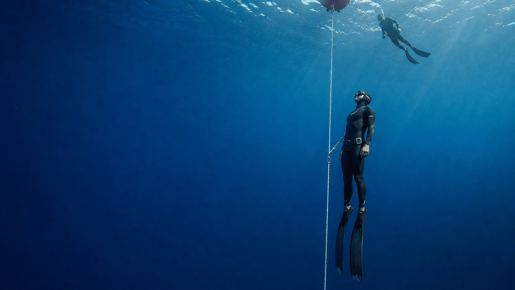 Professional freediver training on a dive line with a safety diver · AI concept image